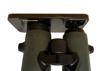 Smartphone bevestigd aan een verrekijker met de Bino Adapter van BINOVIEW voor het maken van foto’s en video’s door de kijker
